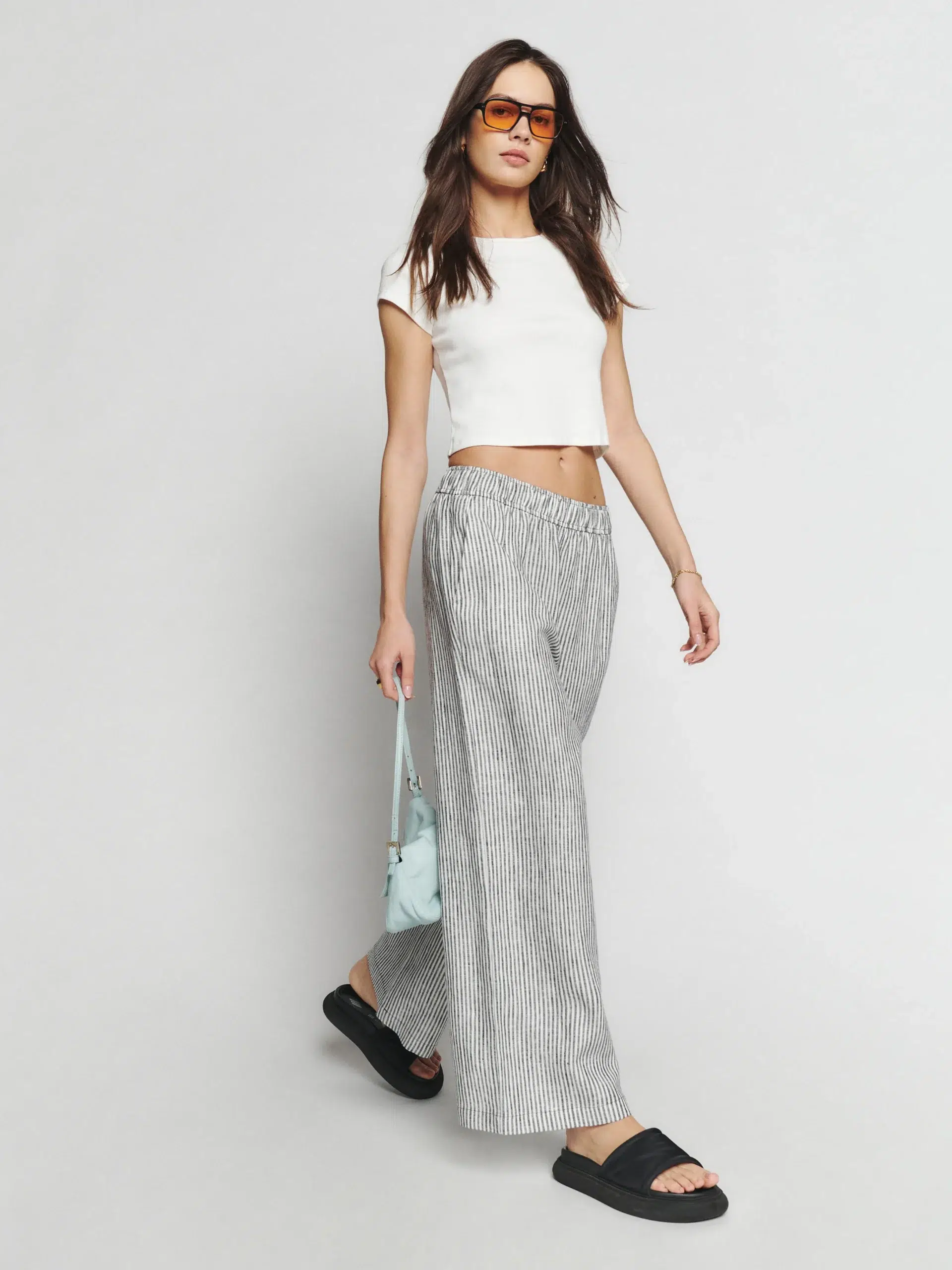 A petite model in a white crop and wide leg pin striped pants.