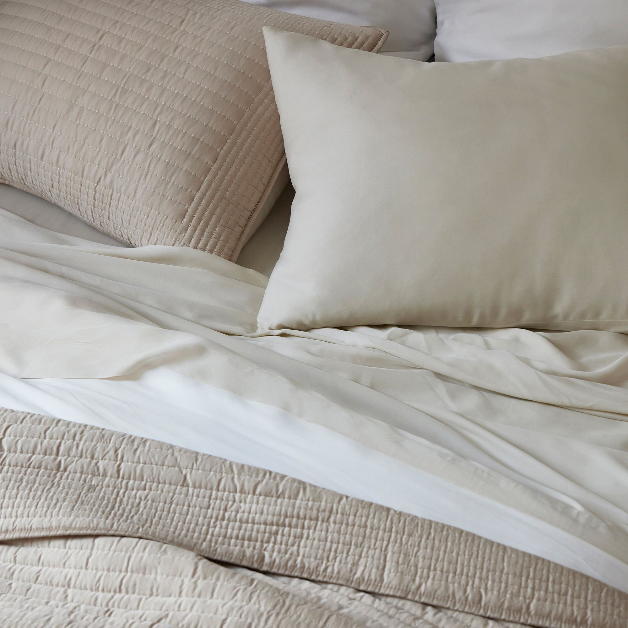 A bed made in neutral Tencel bedding.