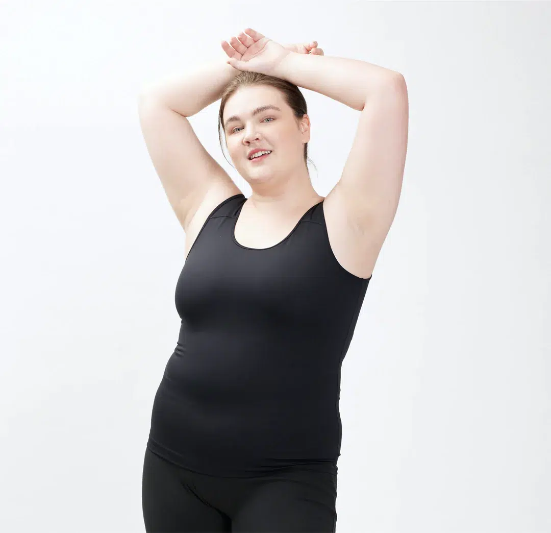 A plus size model in a black tank and leggings.
