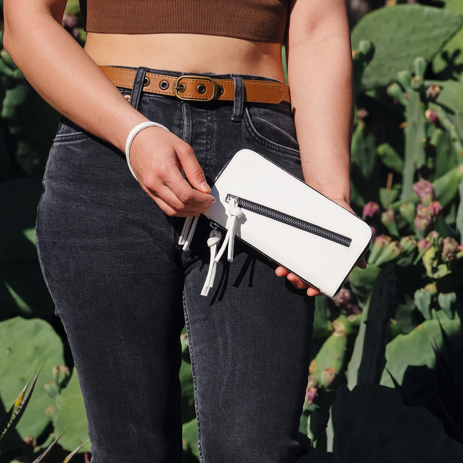 A model holds a white zippered wallet. 