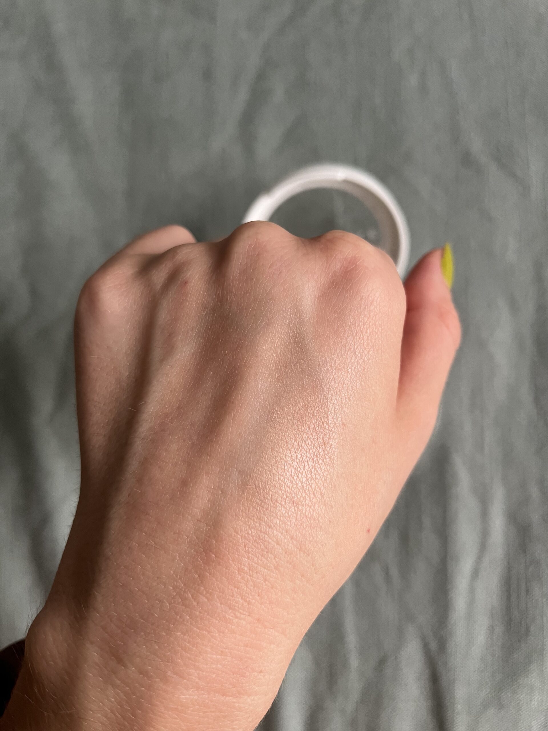 A sample of Well People powder foundation on the back of a hand. 