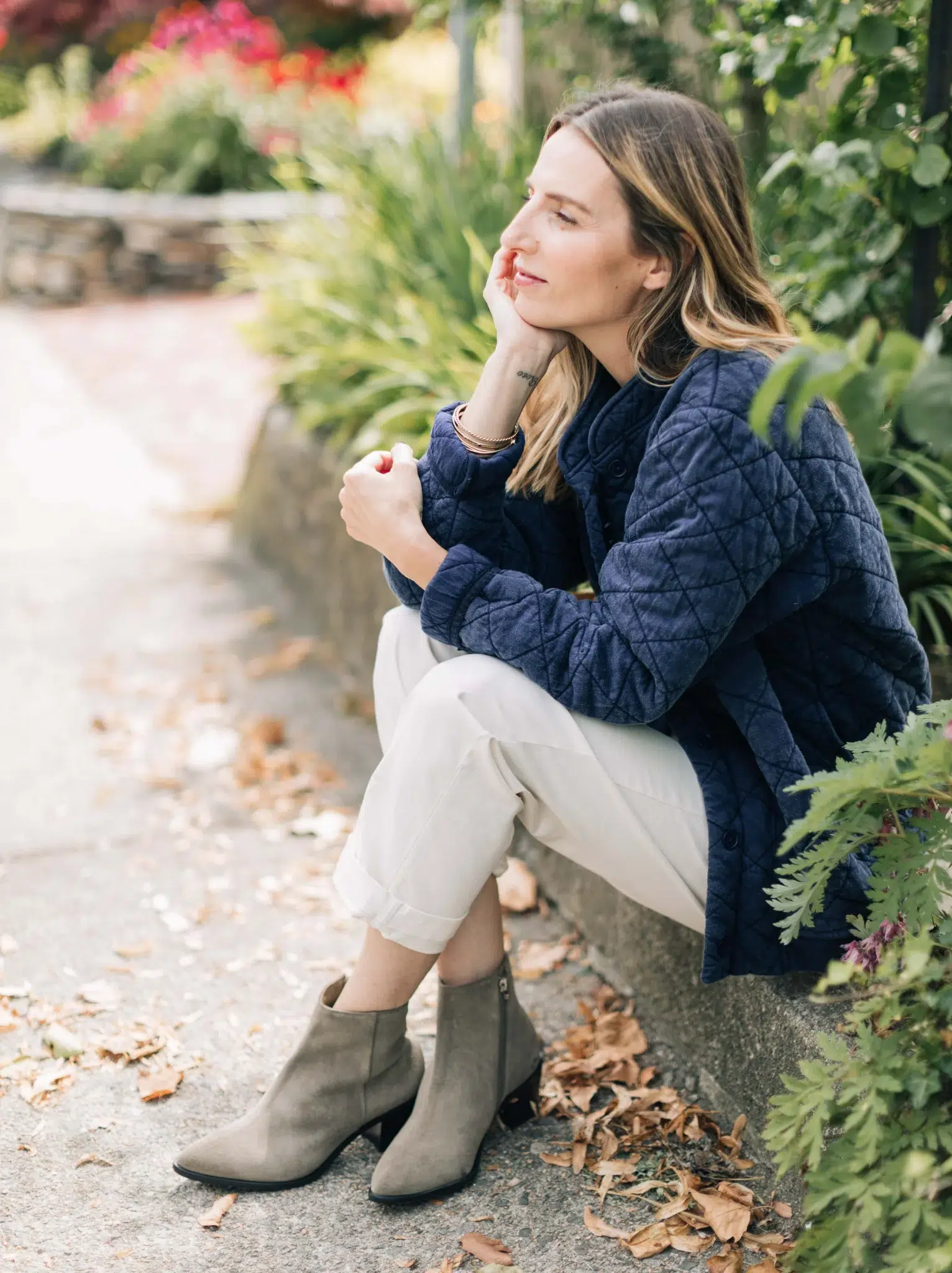 A model sitting on a curb in ABLE sustainable ankle boots. 