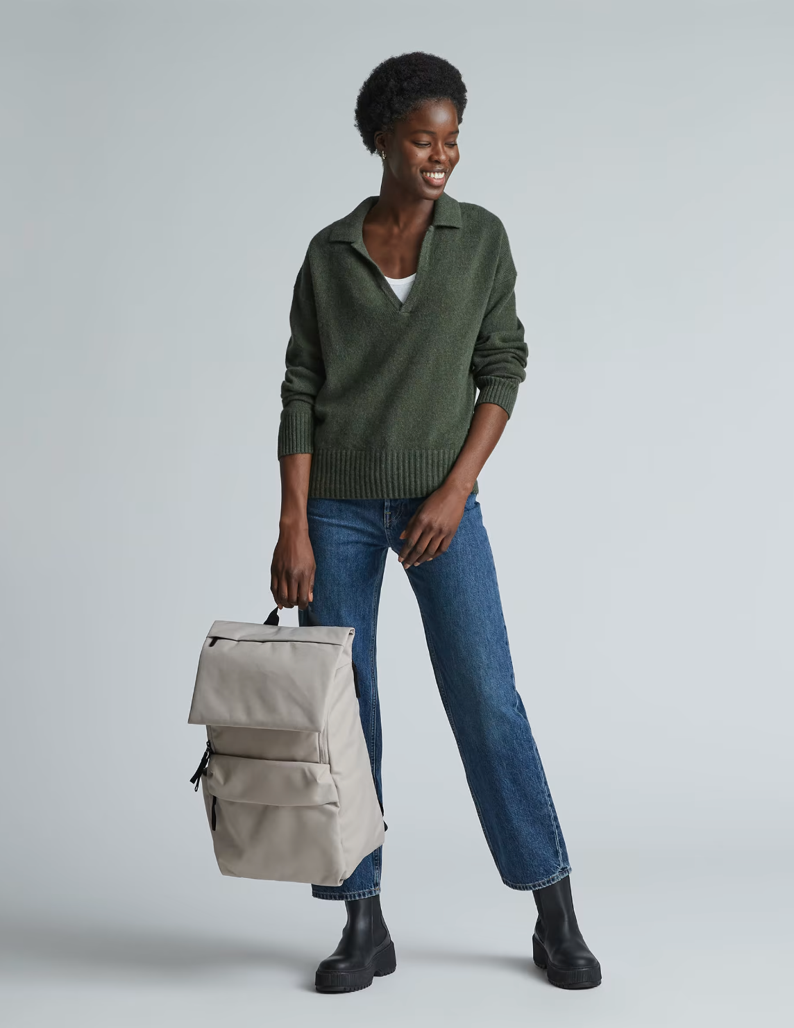 A model holds the Everlane ReNew Transit Backpack by its handles.