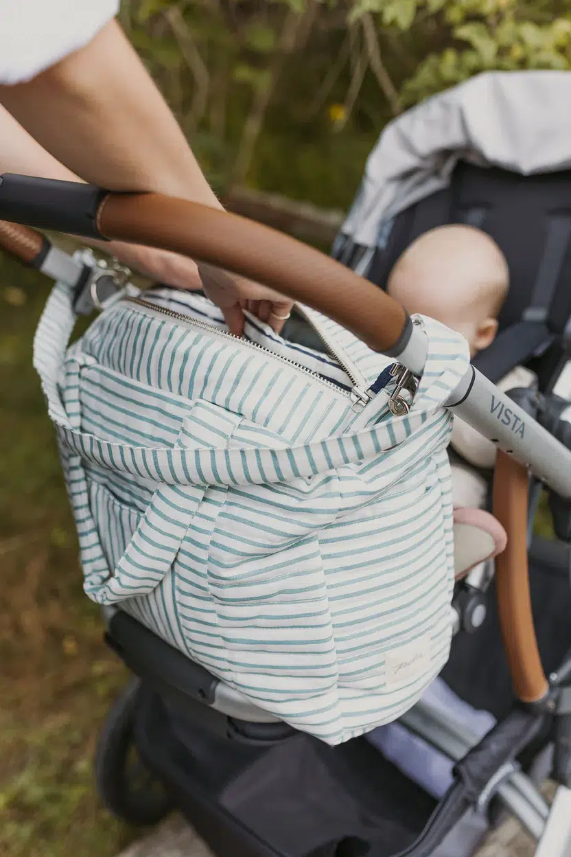 The Pehr Diaper Bag hanging on the handles of a stroller. 