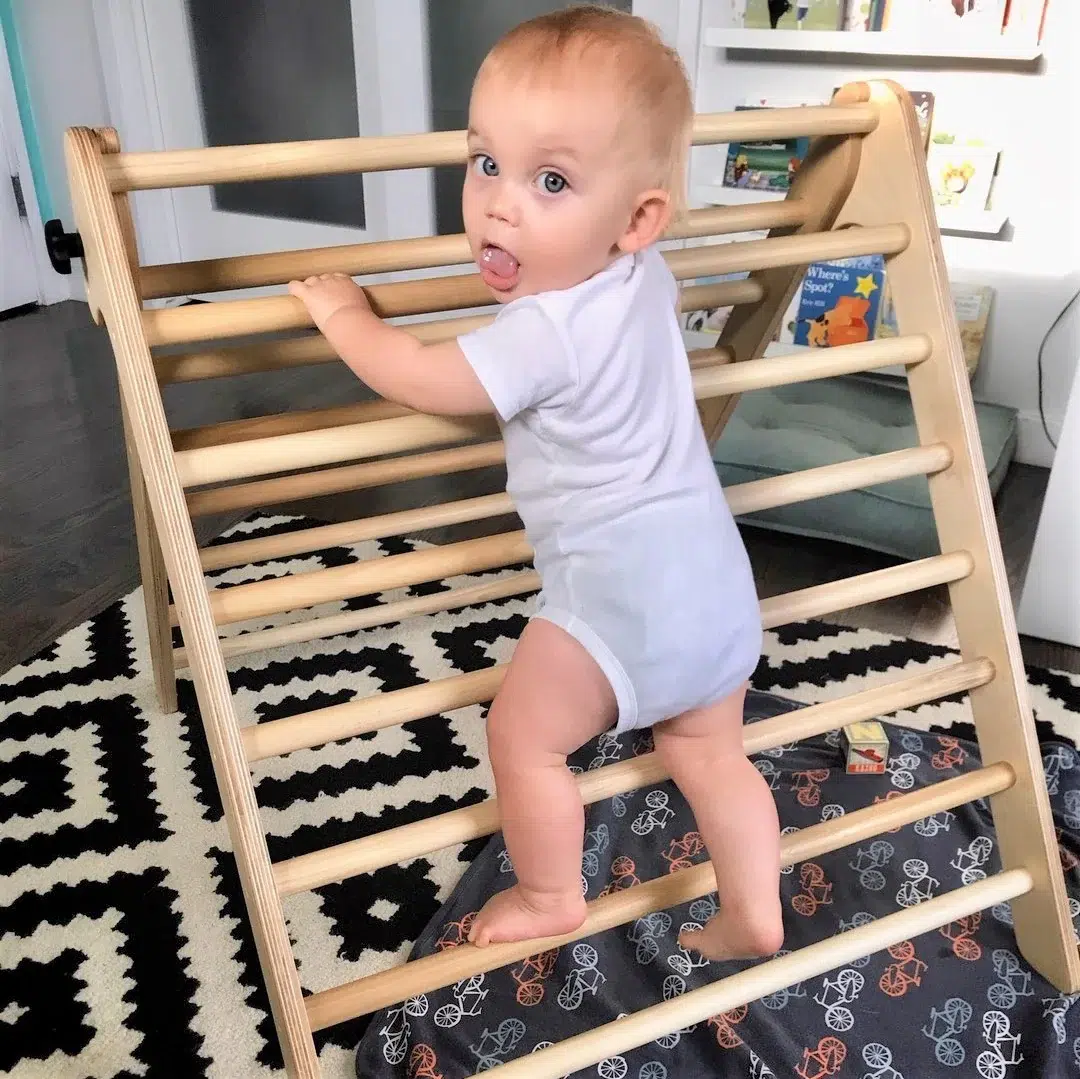 A baby climbs a Pikler triangle. 