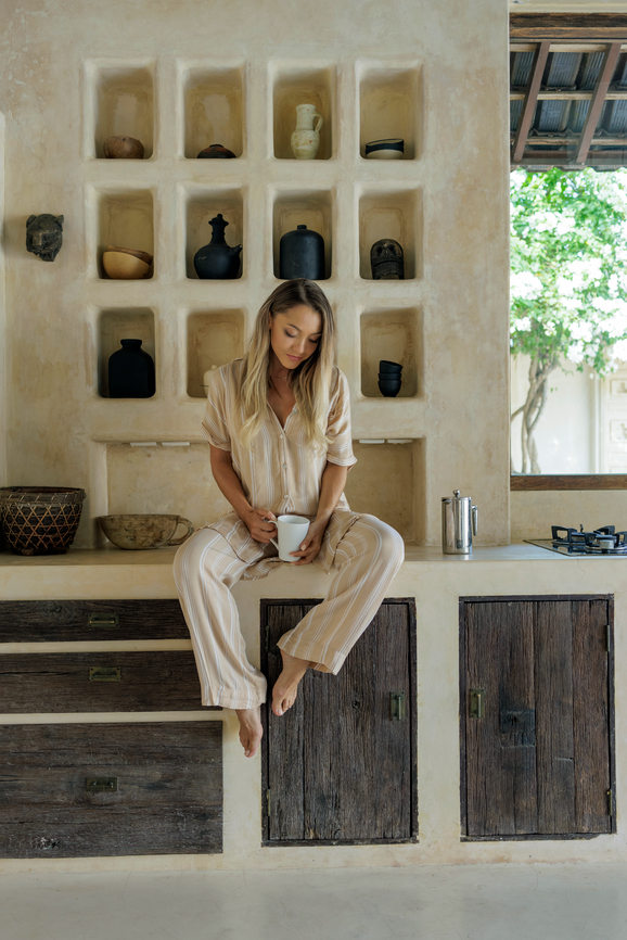 Portraiture of a blonde woman in the kitchen in her pyjamas.