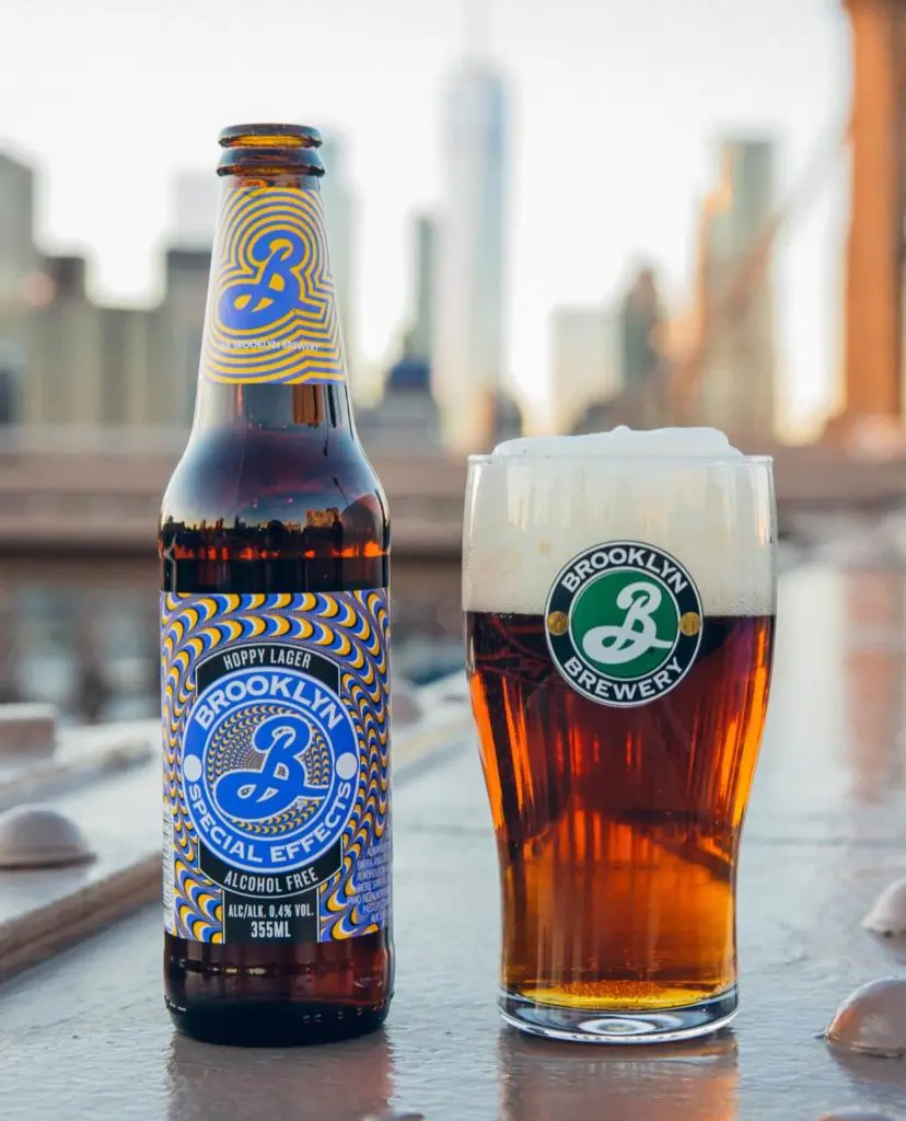A bottle of Brooklyn Brewery Hoppy Lager next to a glass of the product.