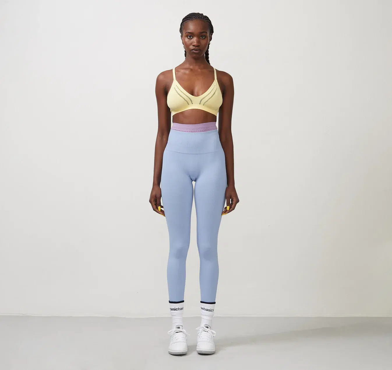 A model wears a sports bra and light blue cotton leggings. 