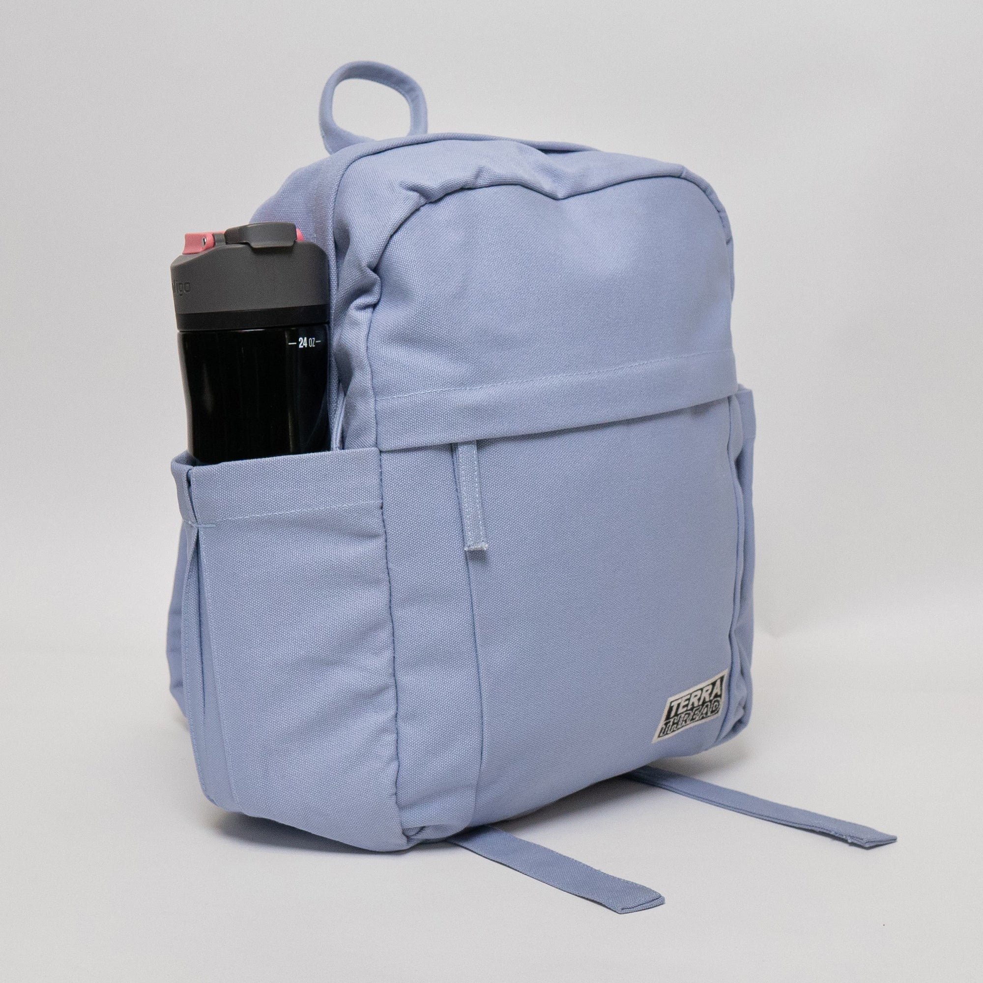 A light blue Terra Thread backpack with a waterbottle in the side pocket.