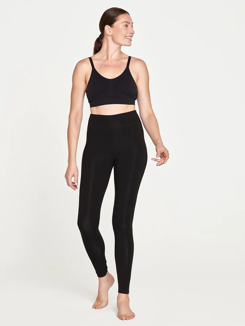 A model wearing a black organic activewear leggings set by thought.
