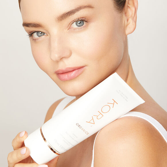 Model Miranda Kerr holding a bottle of Kora Organics nontoxic self-tanner