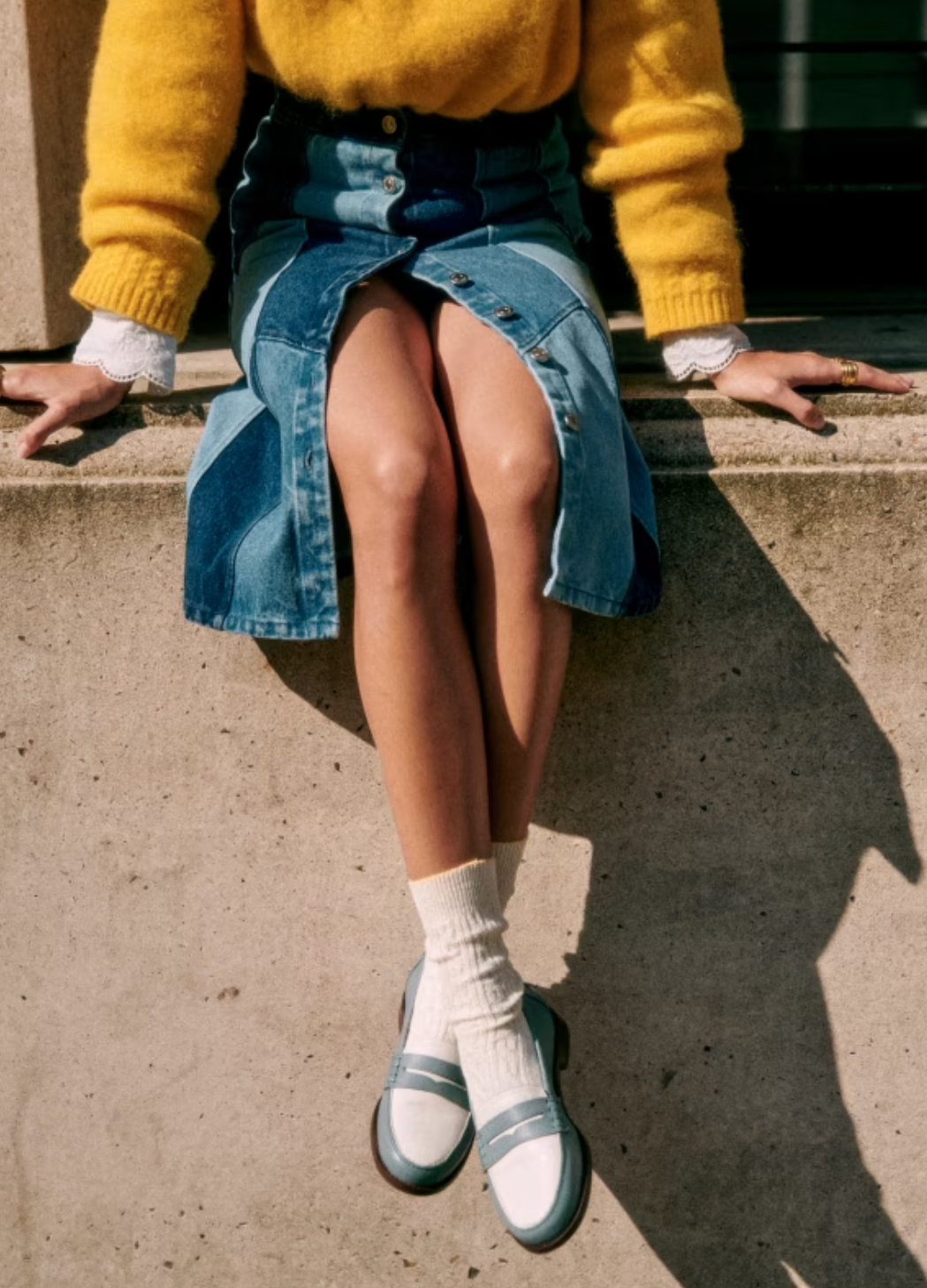 A model wearing blue and white penny sustainable loafers from Sezane. 