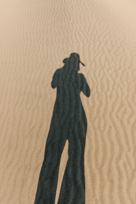 shadow of person wearing a hat on the ground in a desert