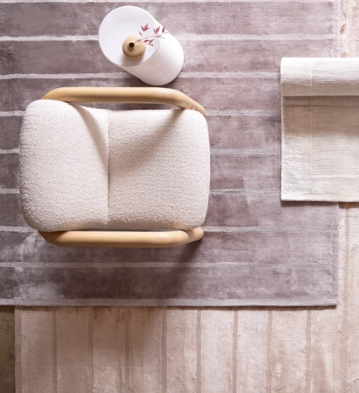 An aerial shot of a West Elm nontoxic striped rug with a chair and side table sitting on it. 