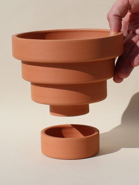 A hand holding up Front Range's Terracotta Steps Plant Pot