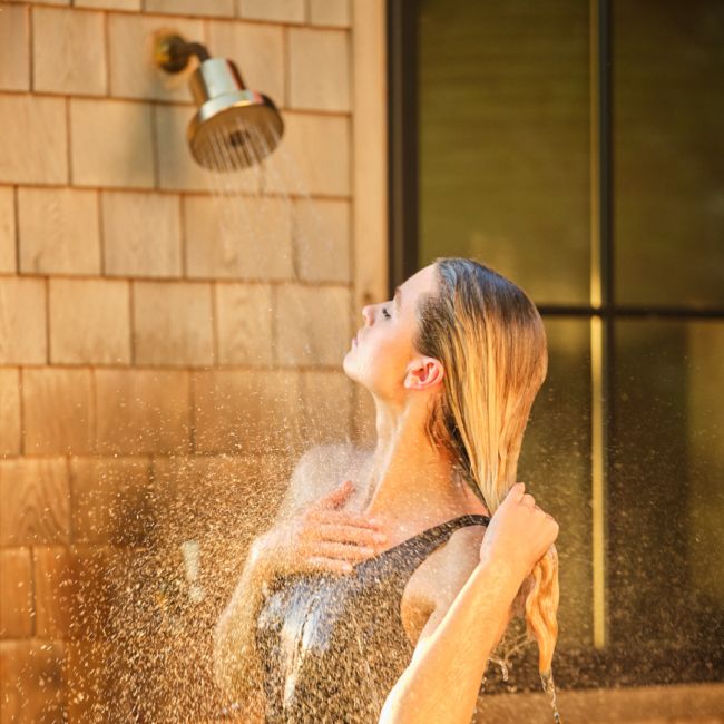 A model in a shower with a gold Jolie filtered showerhead. 