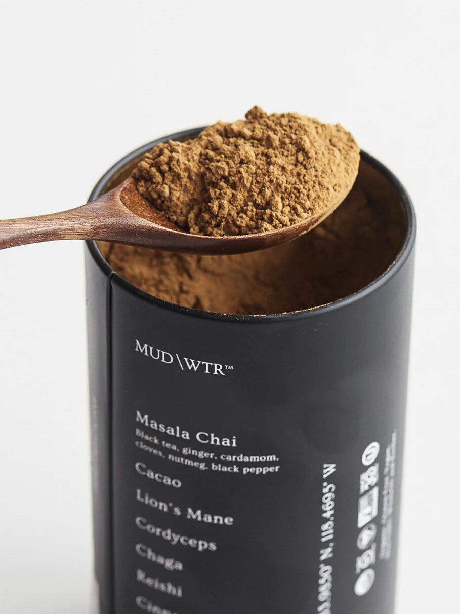 A wooden spoon removing a scoop of Mud\Wtr coffee alternative from its container.