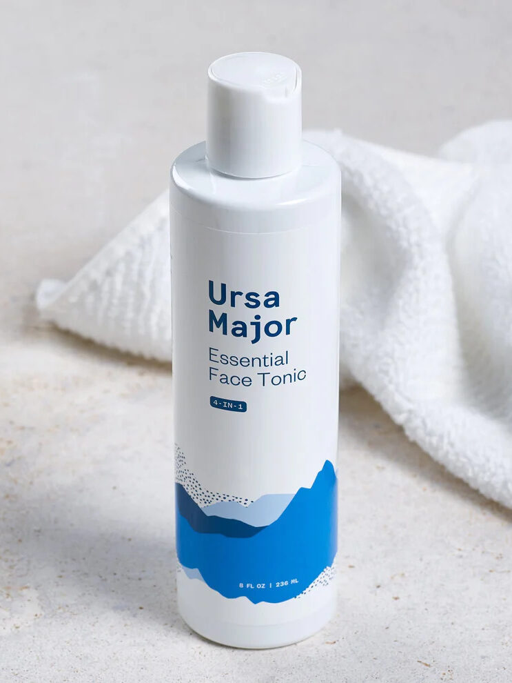 Ursa Major's Essential Face Tonic set on a grey counter with a crumpled white towel behind it. 