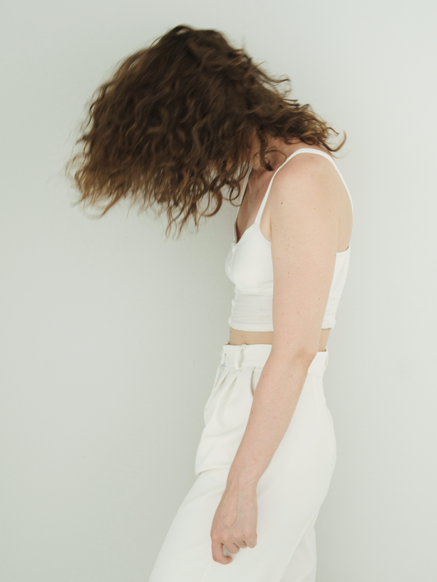 A woman with curly hair shakes her curly hair. Photo with blur