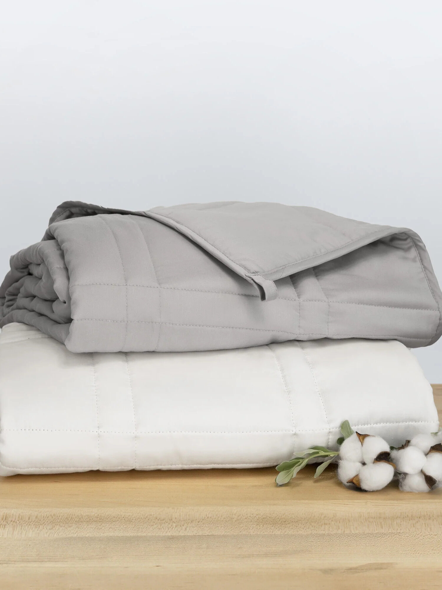 Two folded Baloo weighted blankets in grey and white stacked on each other. 