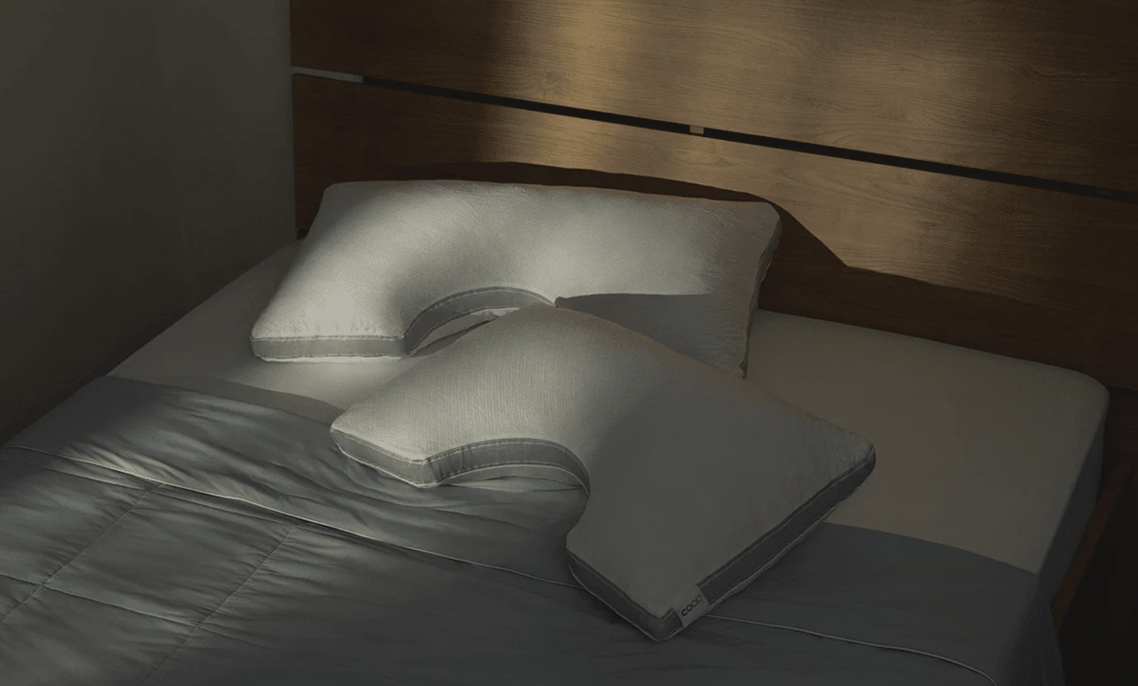 Coop Adjustable Pillows in a pile on a bed