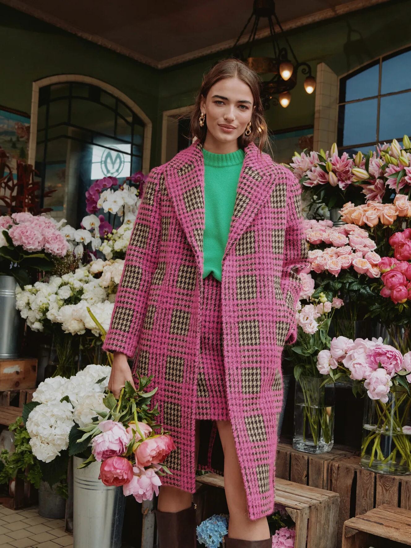 A model wearing a pink and green houndstooth patterned mid-length pea coat by Boden. 