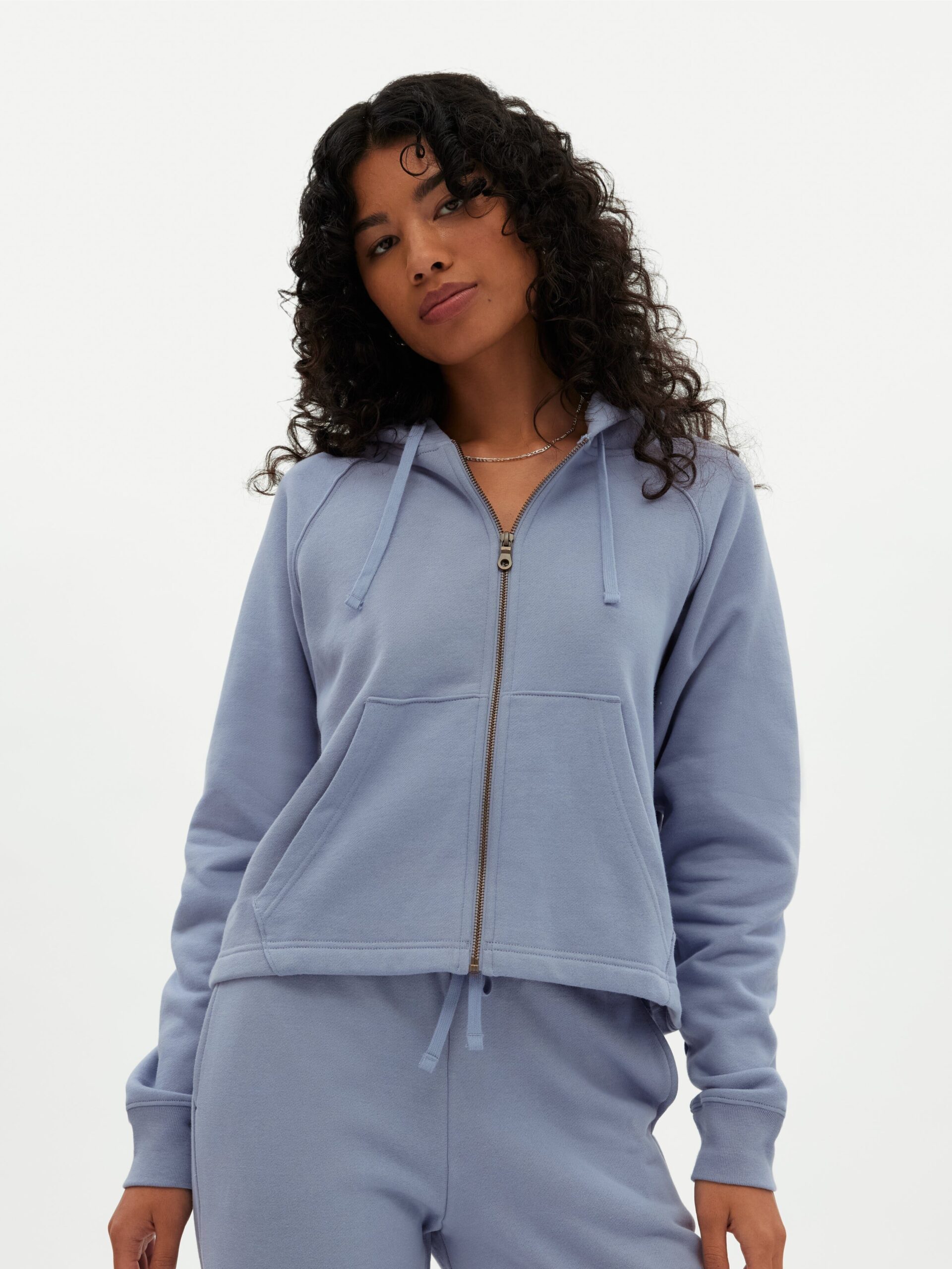 A model wearing a periwinkle blue zip up sweat set by Girlfriend Collective.