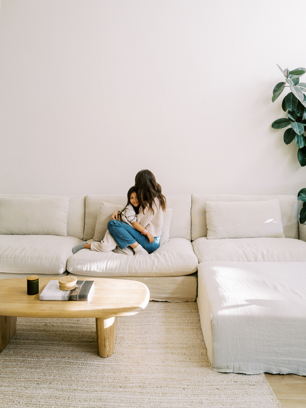 Mom and young daughter together on couch in modern style living room