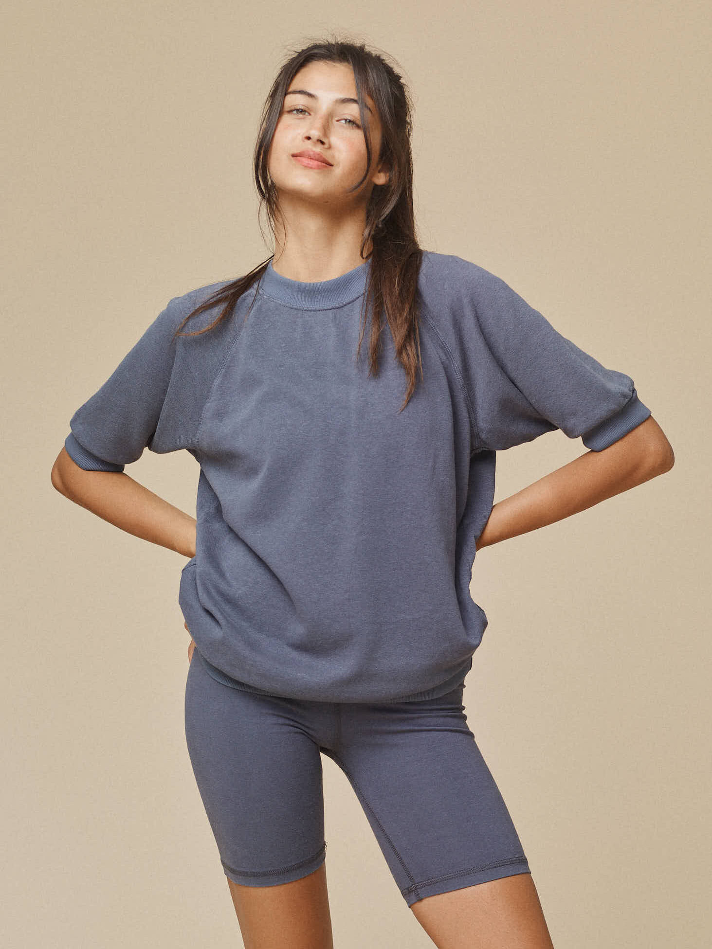 A model wearing a dark blue-grey short sleeve crewneck and biker short set by Jungmaven.