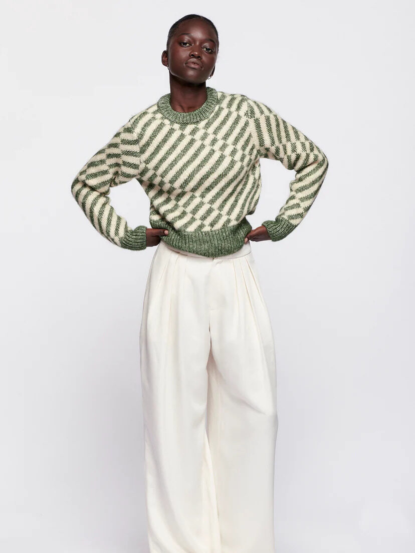 A model wearing the Asilah Cropped Sweater in green by Kotn.