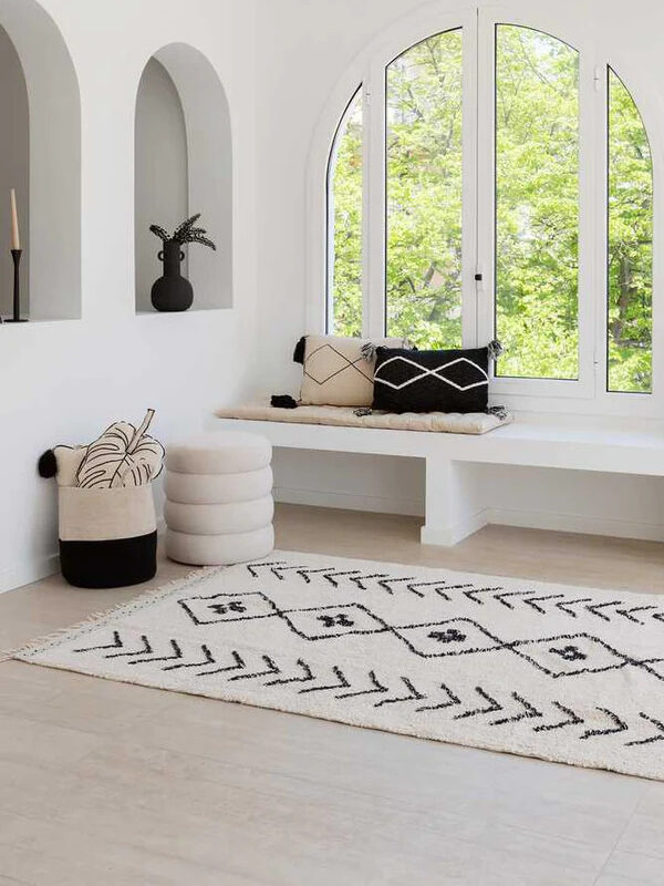 A white and black diamond patterned Lorena Canals rug styled in a white room. 