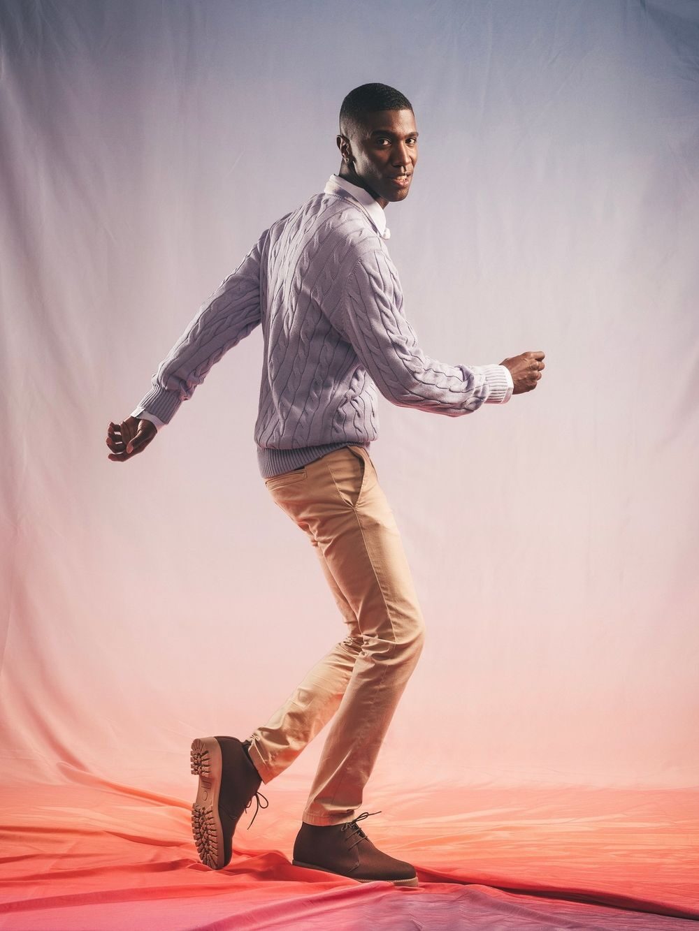 A model wearing a pair of brown Nae Vegan boots with a purple and red sheet behind it.