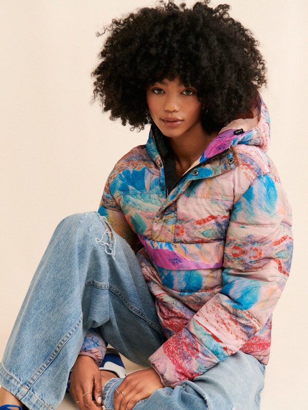 A model wearing a 80's style puffer jacket in an abstract blue and pink pattern from Nuuly.