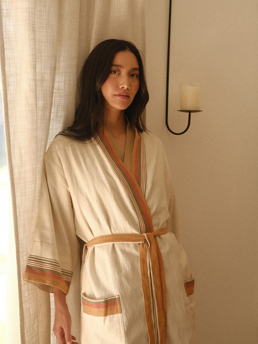 A model in a bedroom wearing Oddbird's cotton and linen robe.