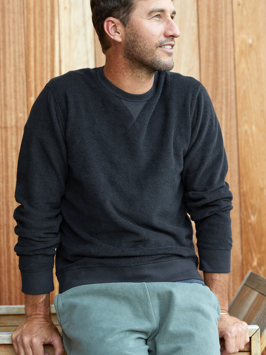 A model wearing an Outerknown crewneck in black.