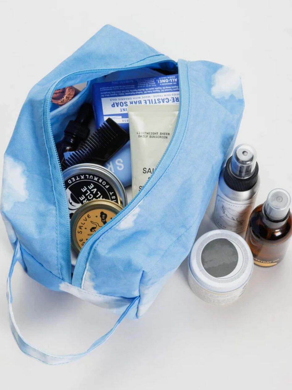 A cloud patterned BAGGU makeup bag filled with a variety of beauty goods found by Plastic Freedom.