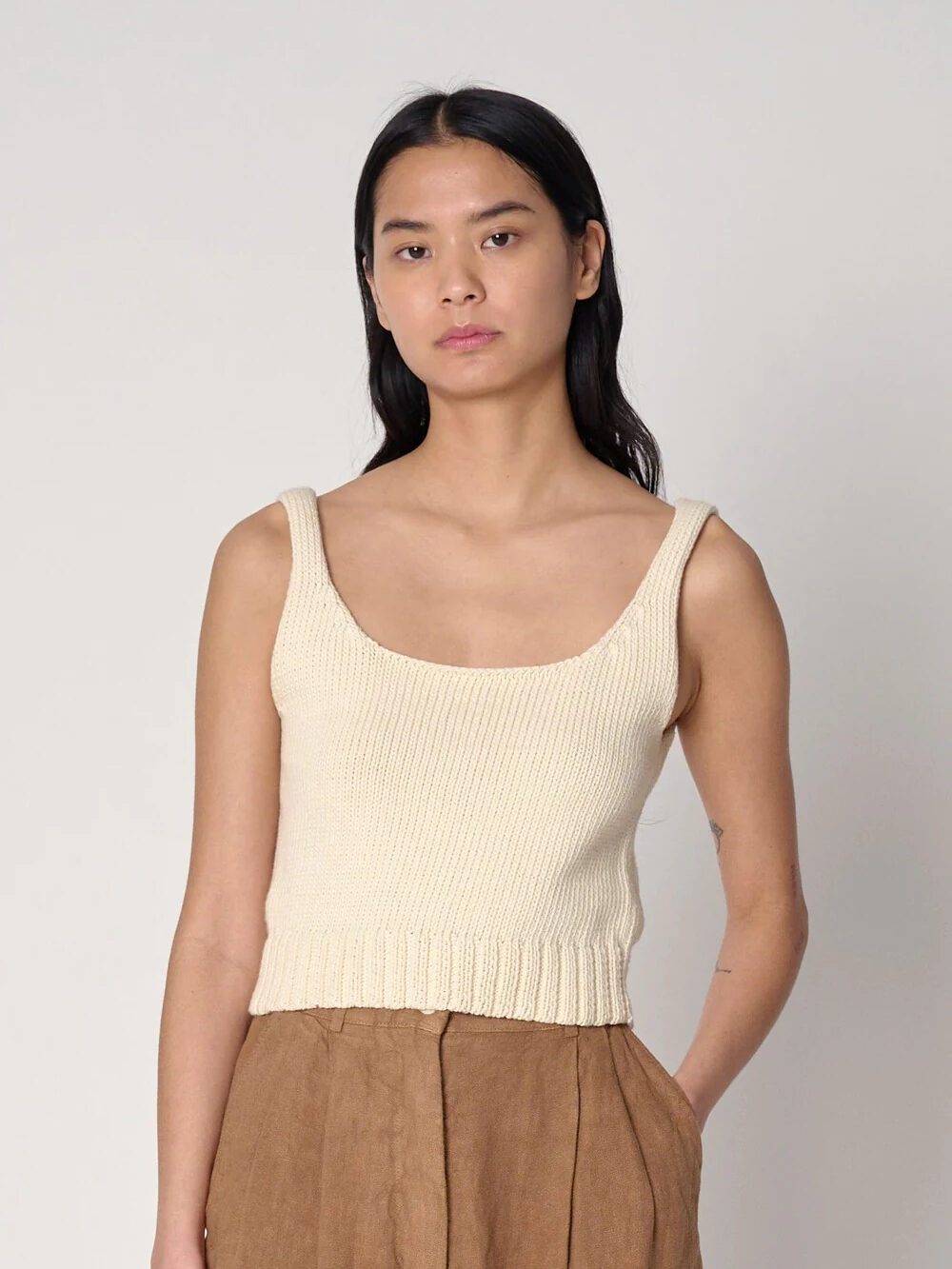 A model wearing a cream knit tank sweater by Shaina Mote.
