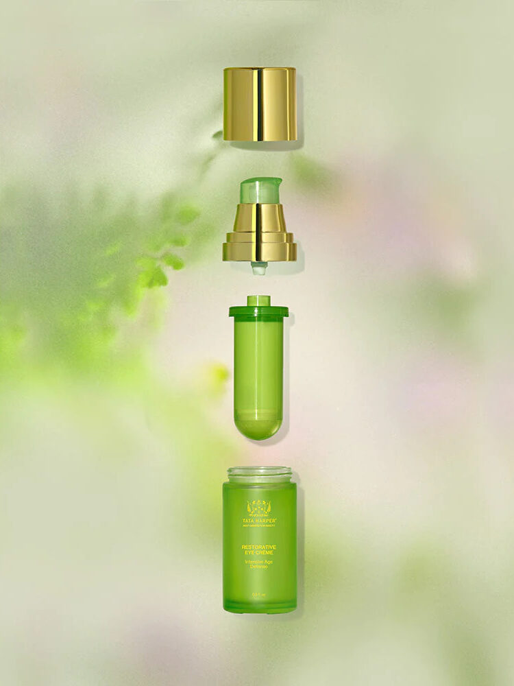 A bottle of Tata Harper's eye cream separated into pieces and stacked over one another in the air to show its refillable components. 