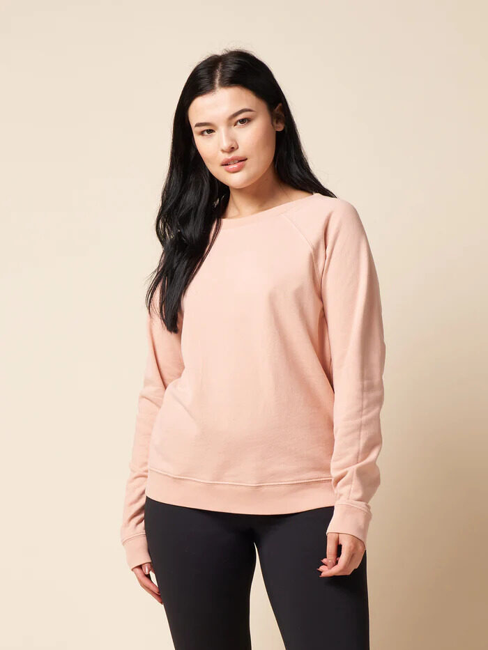 A model wearing a pink The Standard Stitch long-sleeve crewneck.