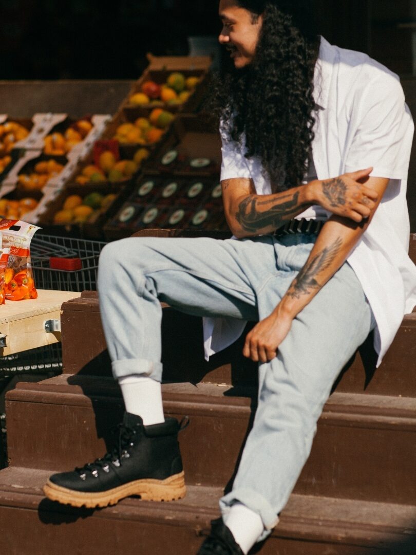 A model seated on steps wearing black Thesus boots.