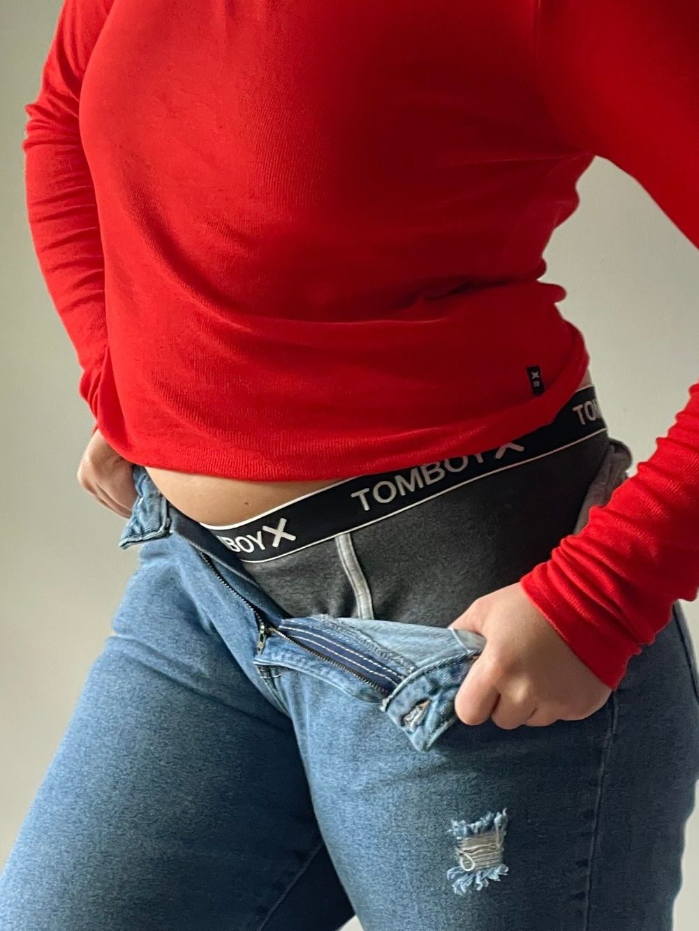 A model wearing TomboyX boxer briefs underneath a pair of jeans.