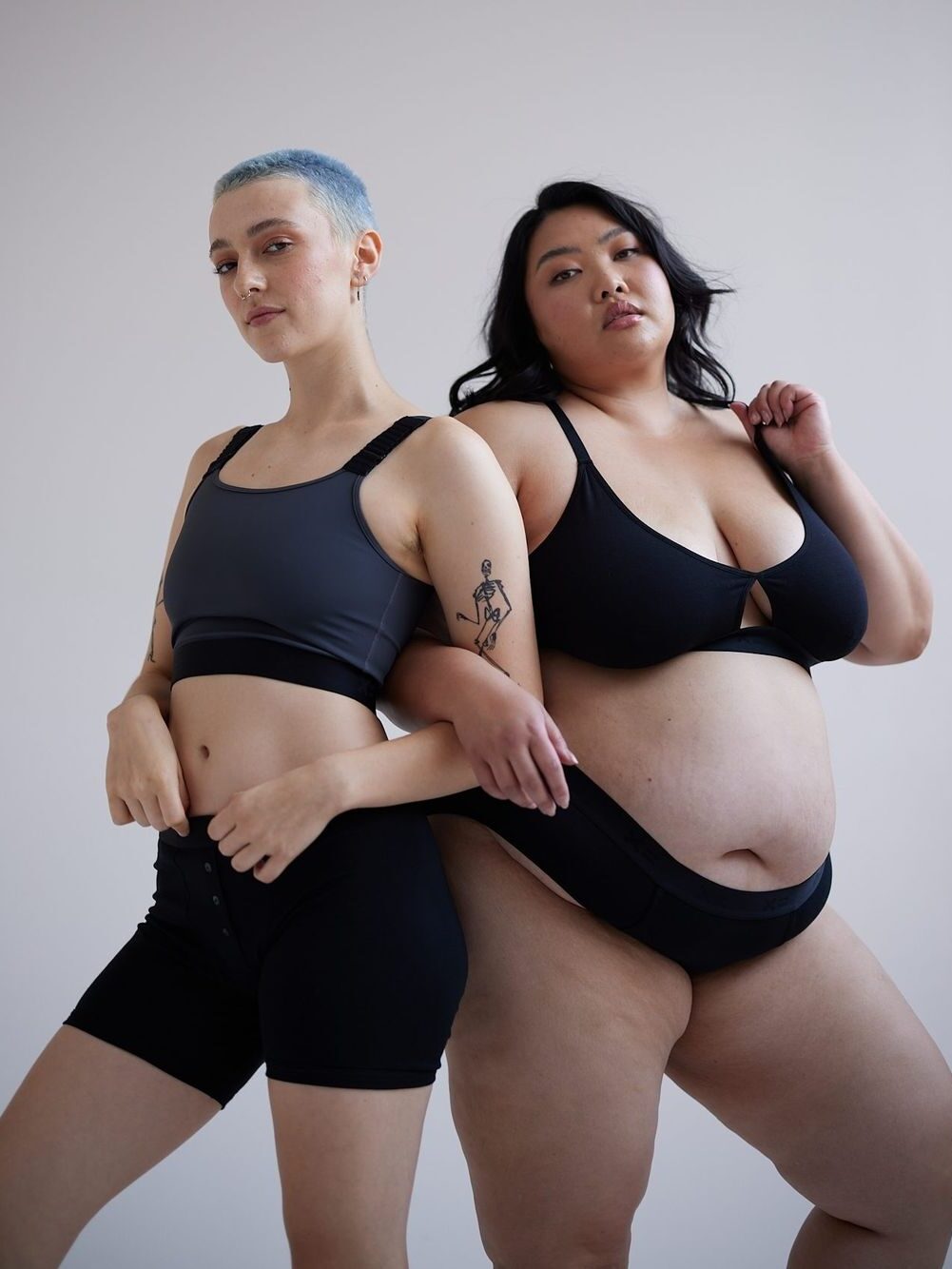 Two models wearing black TomboyX matching intimates sets.