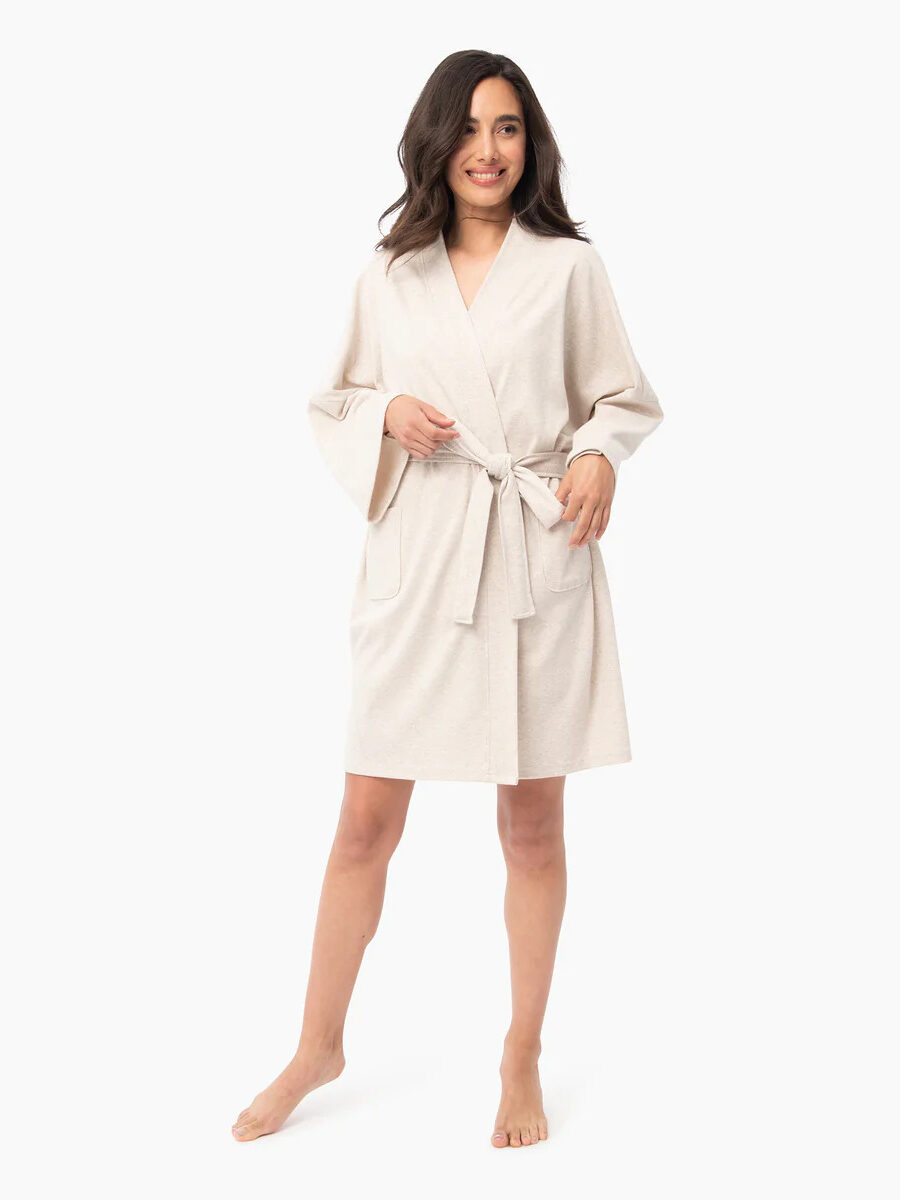 A model wearing Under the Canopy's organic short robe in cream.