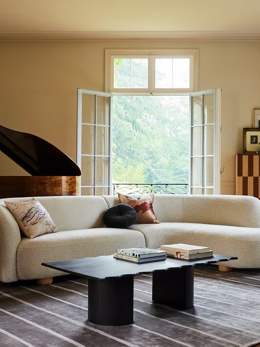 A white West Elm curved structure sofa in a living room.