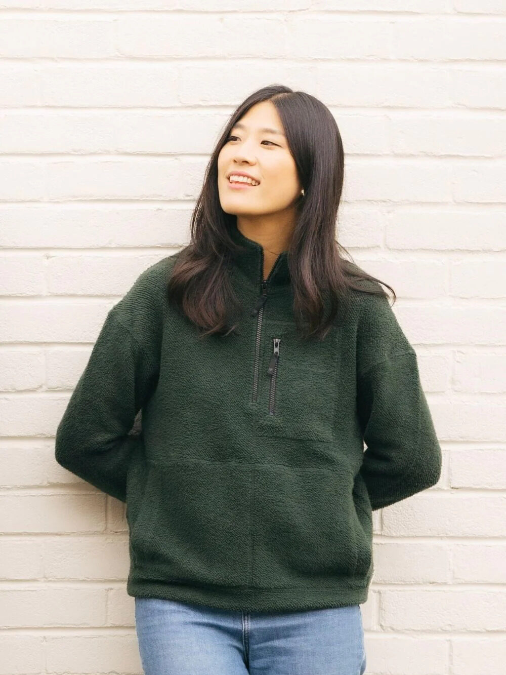 A model wearing a green half-zip organic fleece sweater from Yes Friends