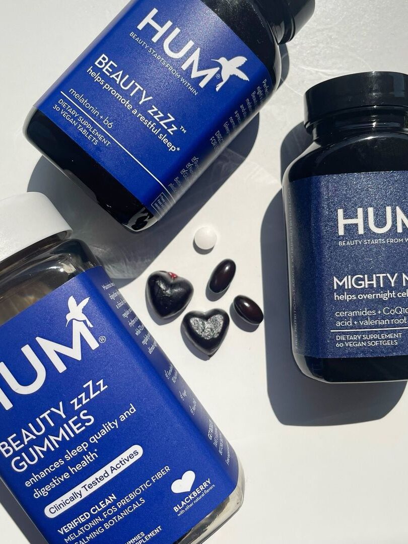 Three bottles of HUM sleep supplements with an example of each gummy/tablet in the center. 
