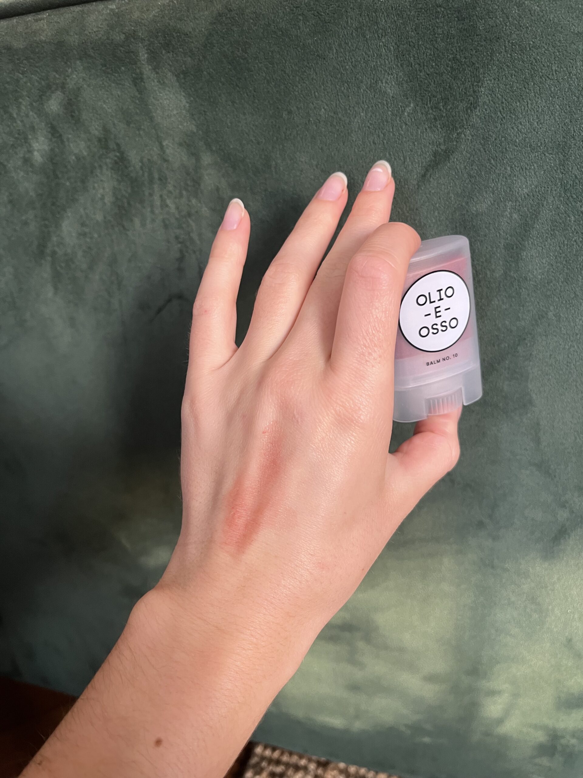 A hand holding Olio E Osso balm