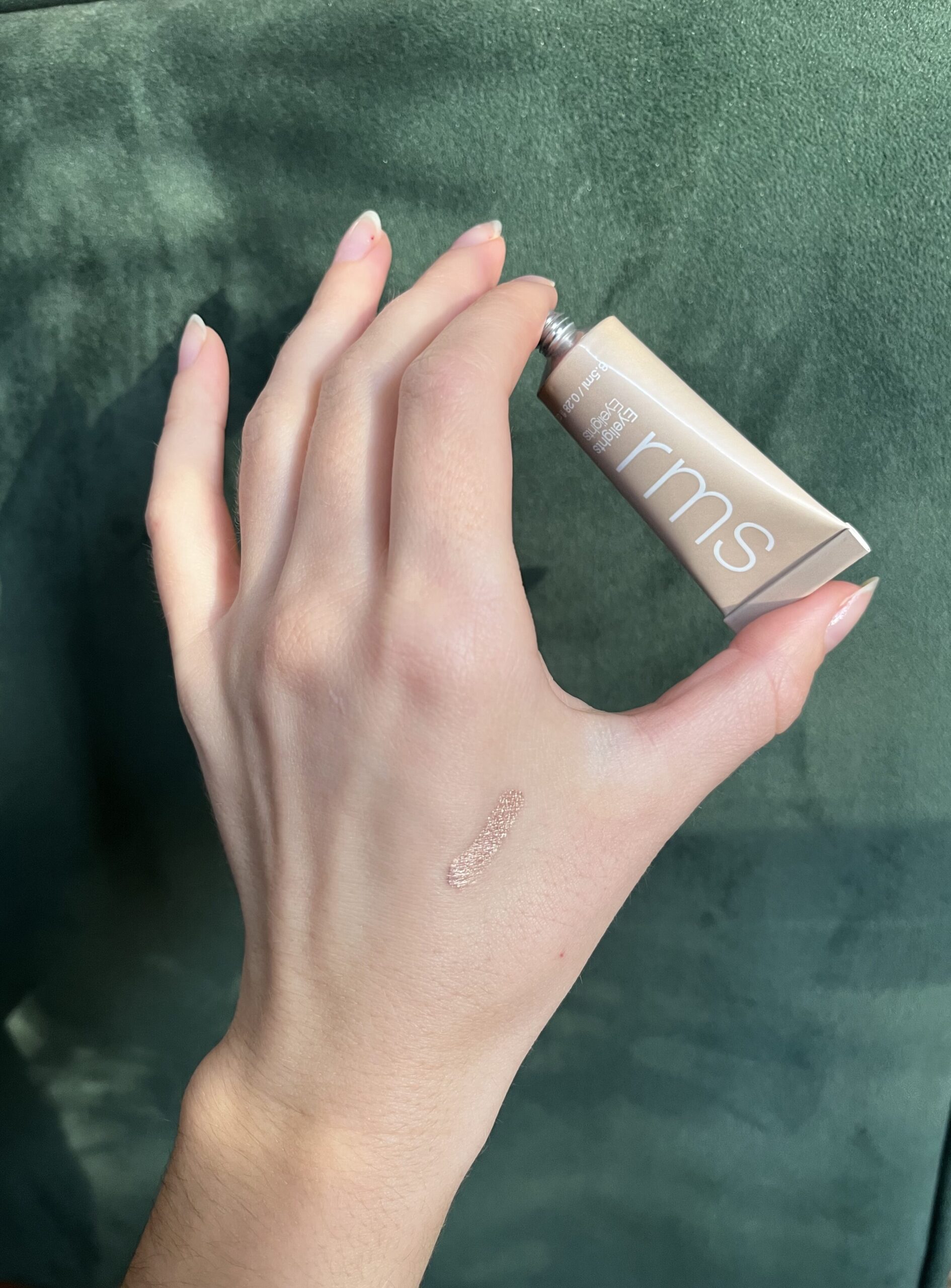 A hand holding RMS Cream Eyeshadow