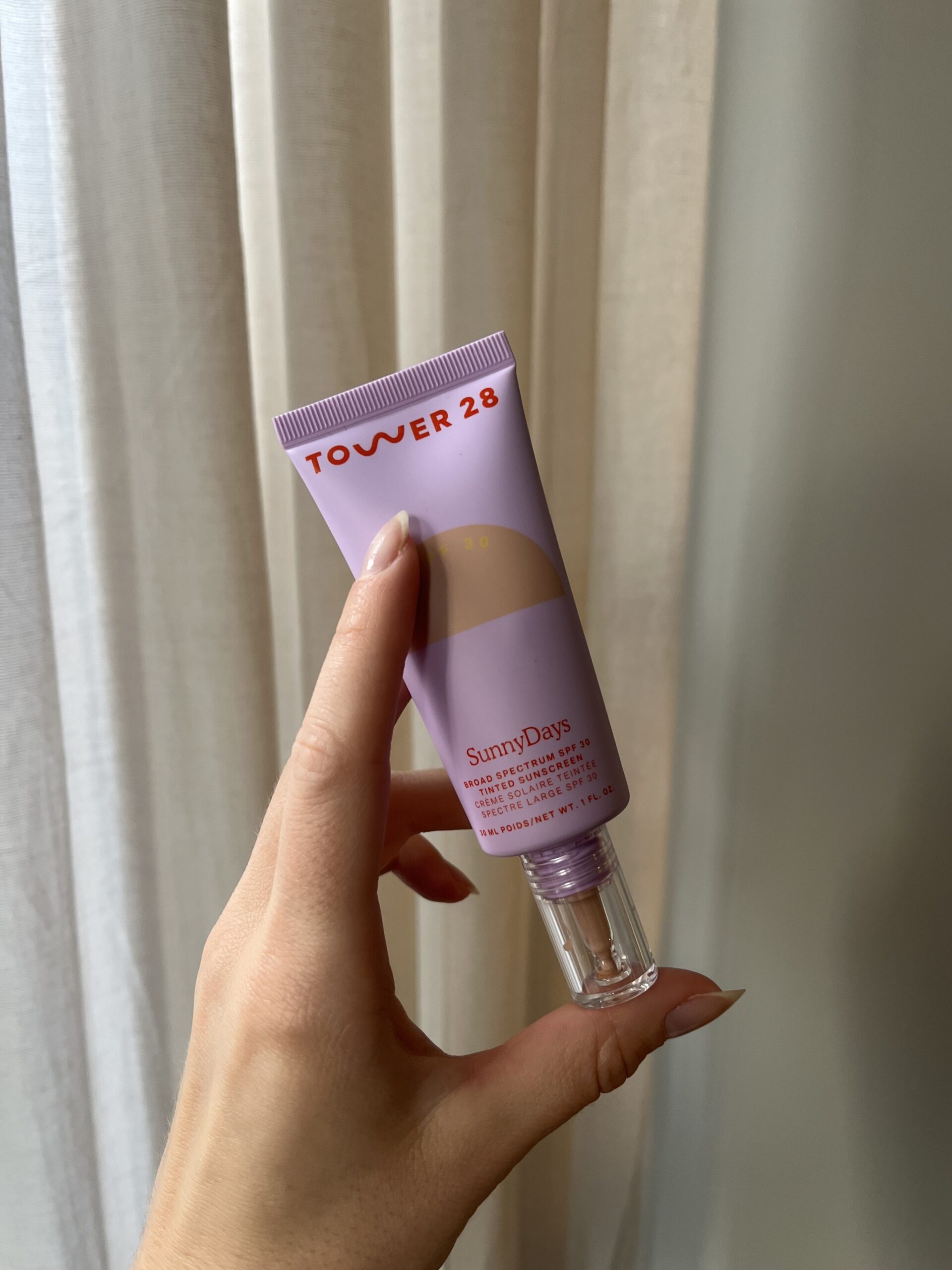 A hand holding Tower 28 SunnyDays Tinted SPF Sunscreen Foundation