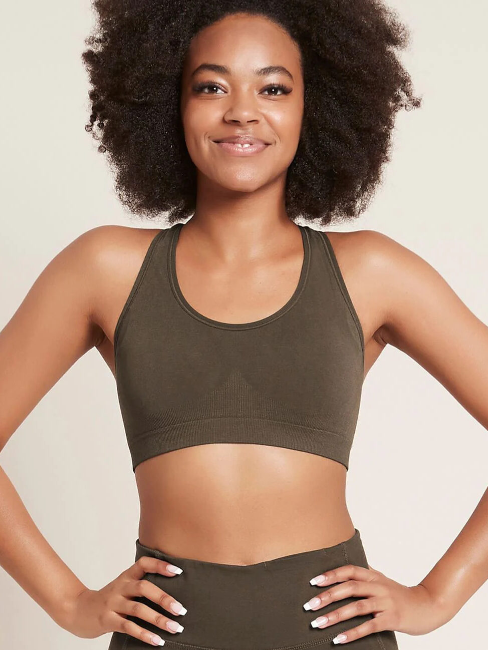 Studio shot of a model wearing a Boody racerback sports bra and matching bottoms in a dark-green-grey shade.